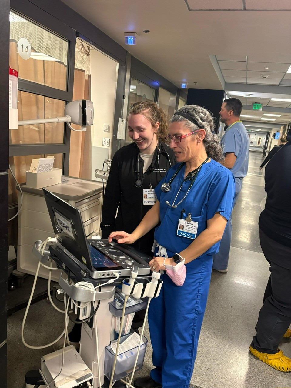 Two female physicians work together using a point of care ultrasound machine. 