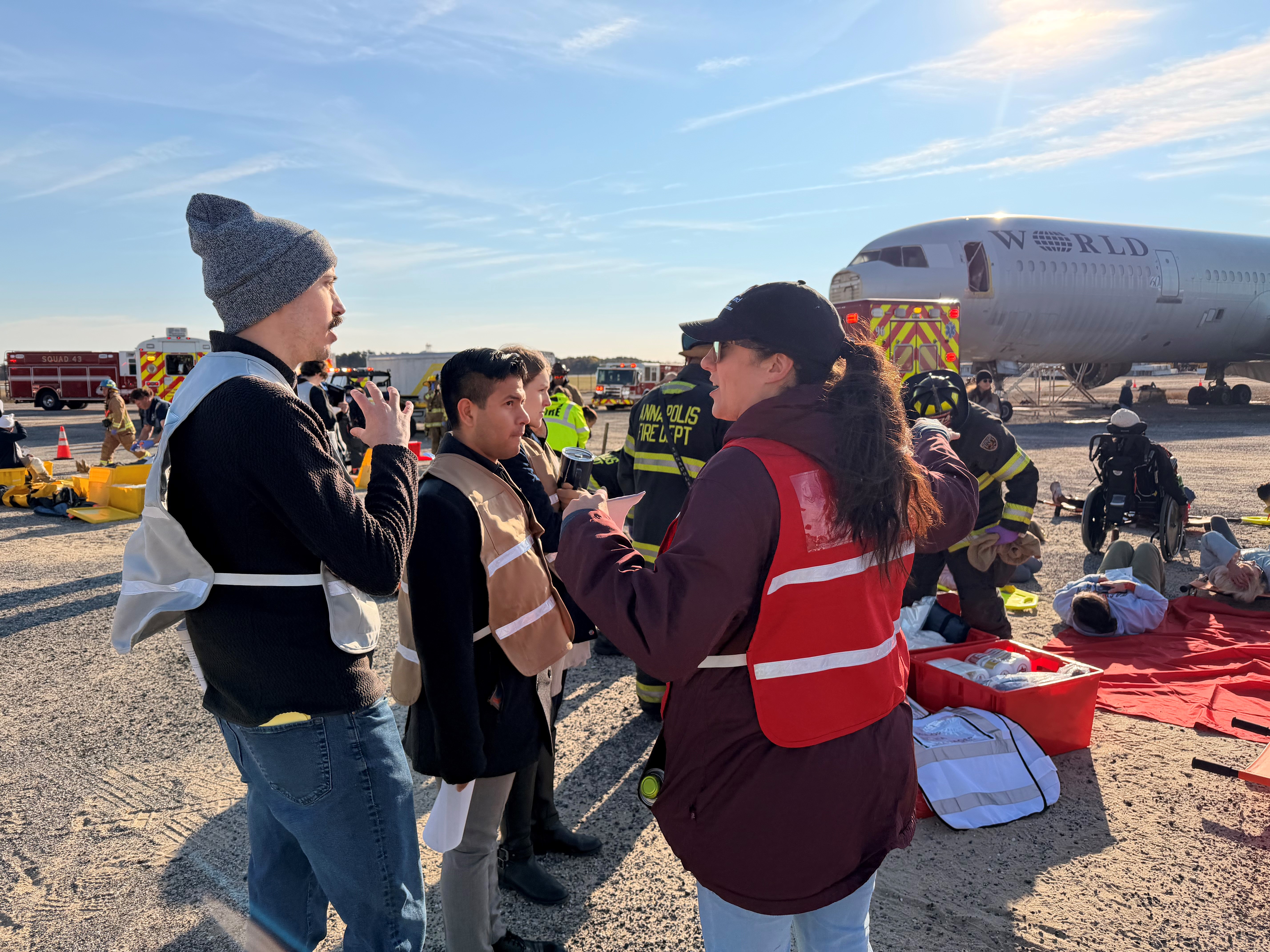Emergency Medicine residents discuss crisis response strategies with a colleague at an outdoor emergency exercise.